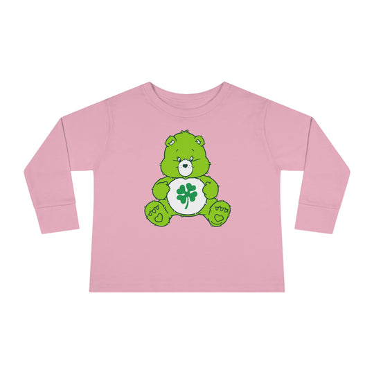 A Lucky Bear Toddler Long Sleeve Tee featuring a pink shirt with a green cartoon bear and clover. Made of 100% combed ringspun cotton, with topstitched ribbed collar for durability and comfort. Toddler unisex fit.