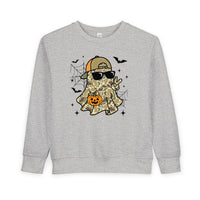 Candy Ghost Toddler Crew sweatshirt features a camo-clad ghost with sunglasses, peace sign, and pumpkin bucket, surrounded by spiderwebs, bats, and sparkles. Cozy and durable design.
