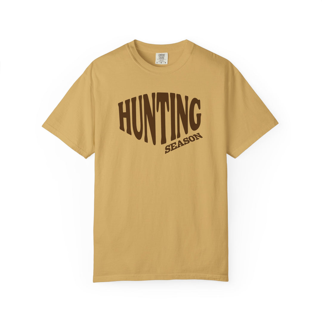 Hunting Season Tee: Muted mustard crew neck T-shirt with HUNTING SEASON in brown letters, offering relaxed fit and durable, soft-washed cotton fabric.
