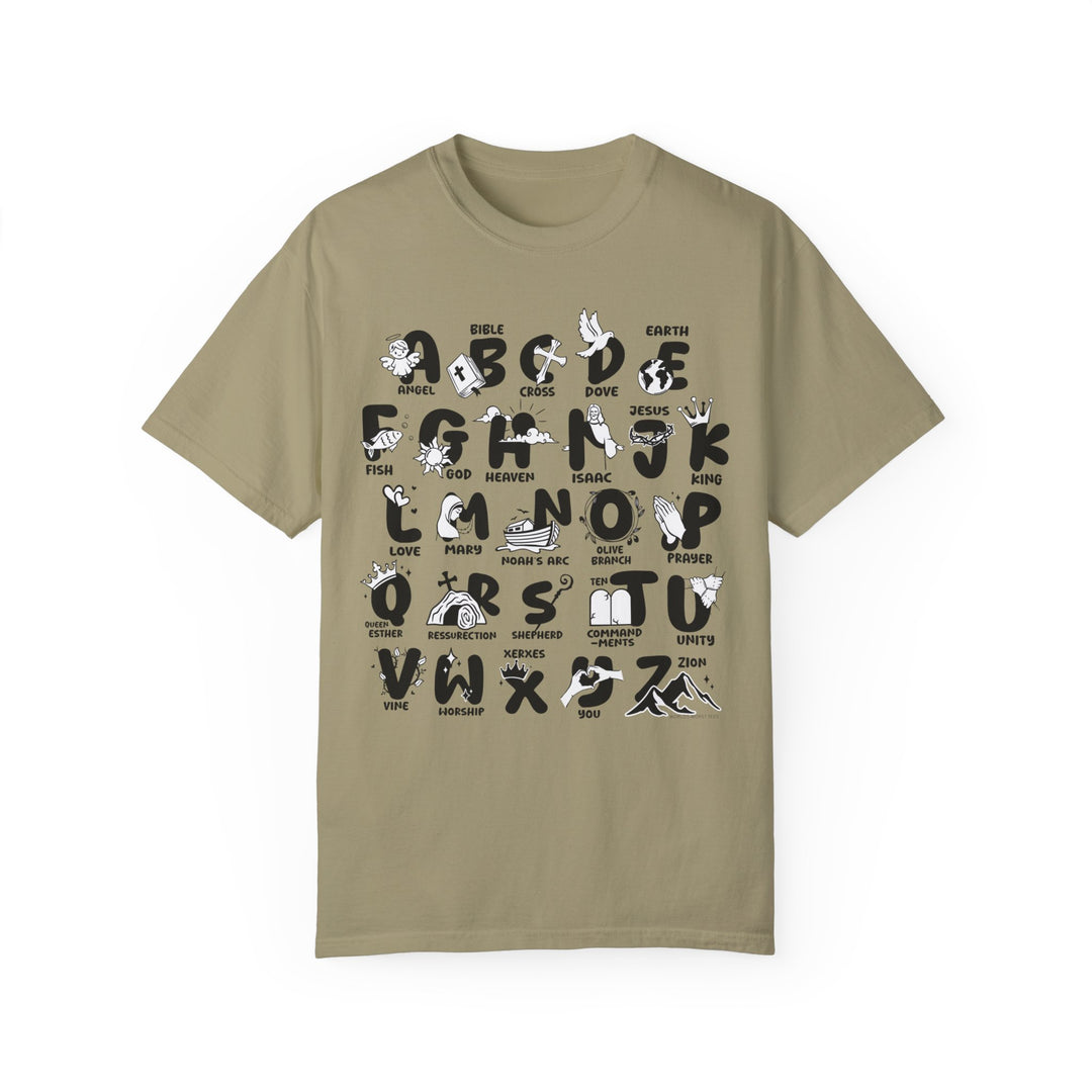 A Bible Alphabet Tee featuring a tan shirt with black and white graphic designs. Made of 100% ring-spun cotton, garment-dyed for extra coziness and durability. Relaxed fit with double-needle stitching for a daily staple.