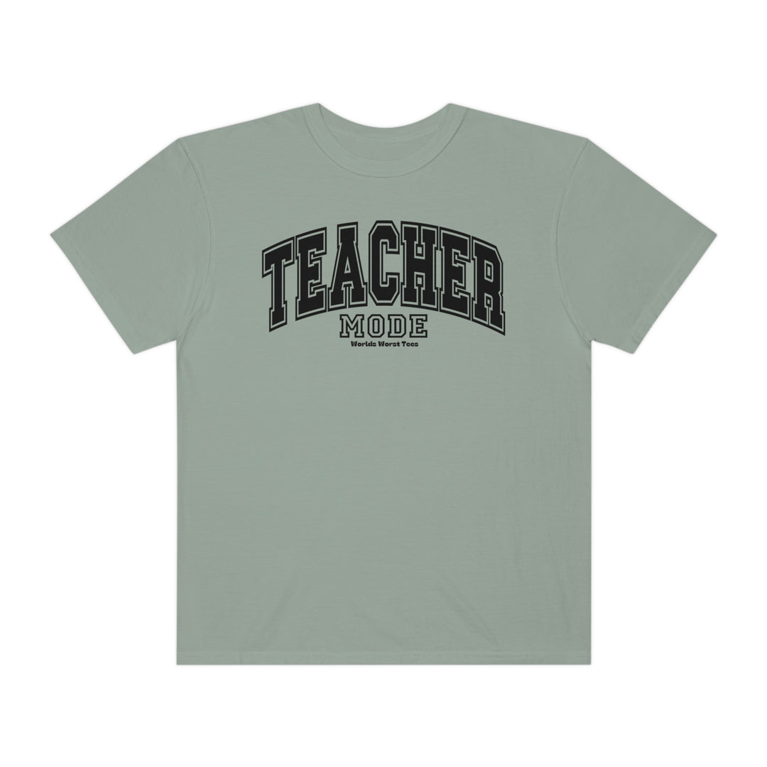A grey t-shirt with black text, featuring the Teacher Mode Tee design from Worlds Worst Tees. Unisex, relaxed fit, made of 80% ring-spun cotton and 20% polyester. Medium-heavy fabric, garment-dyed, with rolled-forward shoulder.