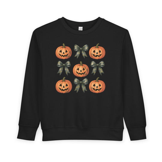 Pumpkins and Bows Toddler Crew: Black sweatshirt featuring a 3×3 grid of Halloween-themed jack-o’-lanterns and camouflage-pattern bows, designed for warmth and durability.