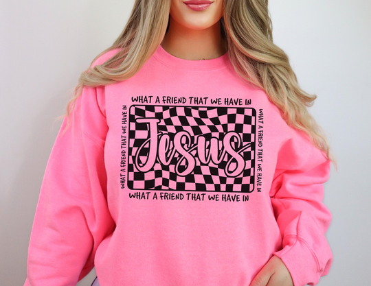 Person wearing a bright pink sweatshirt featuring a wavy black-and-pink checkerboard with Jesus and What a friend that we have in text design.