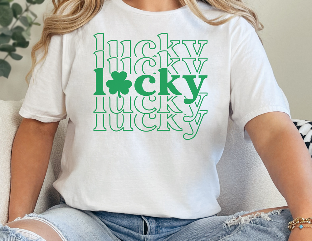 A white tee with green text, featuring a clover design. Unisex heavy cotton tee with no side seams for comfort, ribbed knit collar, and durable tape on shoulders. Classic fit, 100% cotton.
