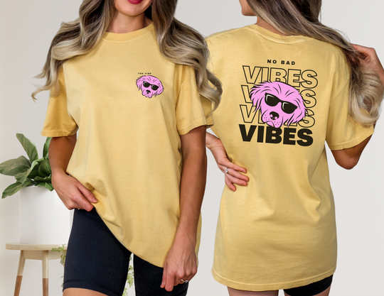 A woman in a yellow Dog Lover Good Vibes Beefy Tee with a pink dog design. Made of 100% cotton, featuring shoulder-to-shoulder taping and double-needle stitching for durability.