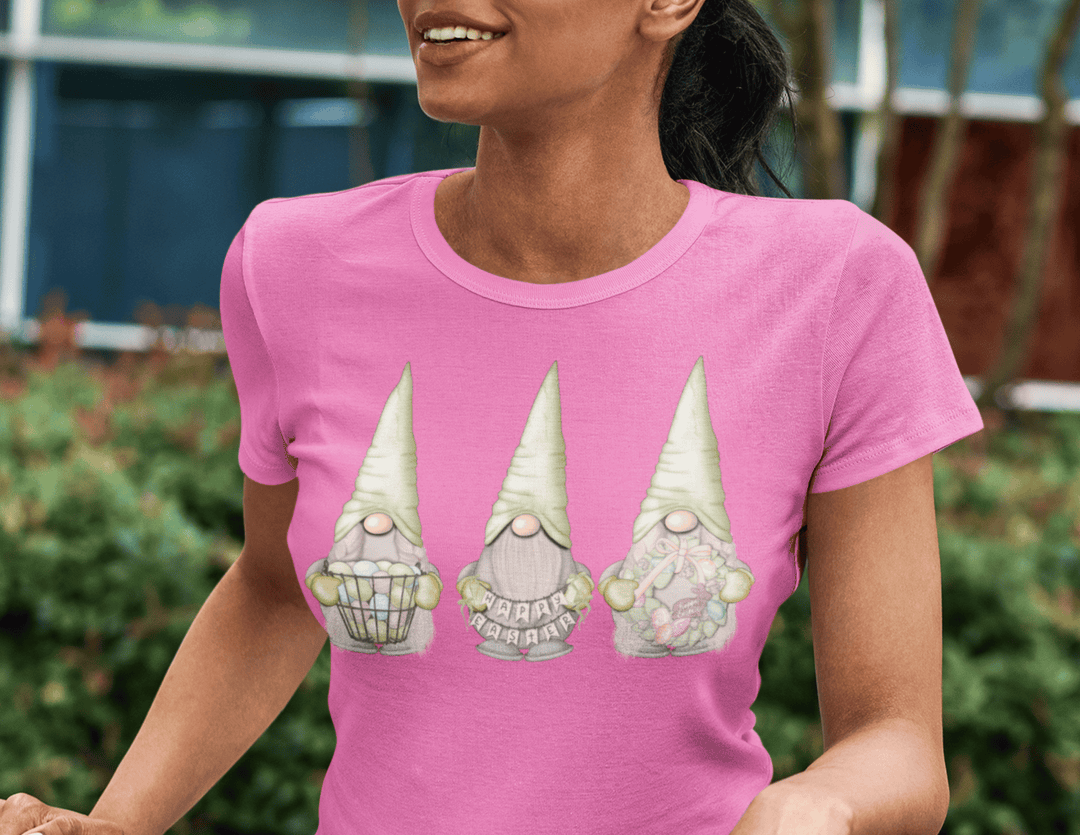 Happy Easter Gnomes Women's Tee featuring three adorable gnomes on a pink shirt. Unisex, 100% cotton, Eurofit, with twill tape shoulders for durability. Perfect for a festive and comfy look.