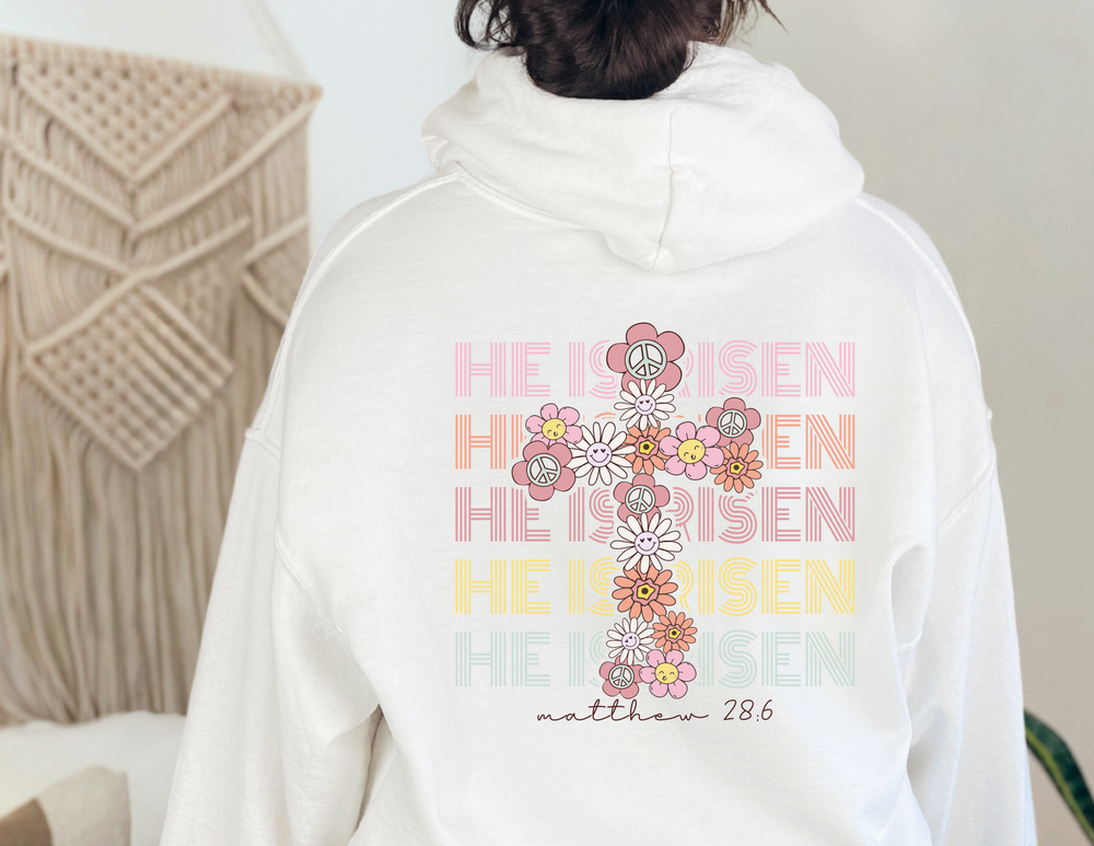 Unisex He is Risen Easter Hoodie, white with cross and floral design. Cotton-polyester blend, kangaroo pocket, classic fit. Ideal for warmth and comfort.