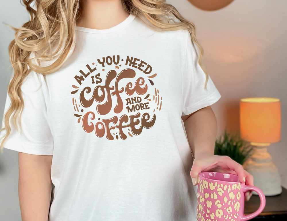 A woman holding a pink mug on a tee. Unisex heavy cotton, no side seams for comfort. Classic fit, ribbed knit collar. Perfect for coffee lovers.