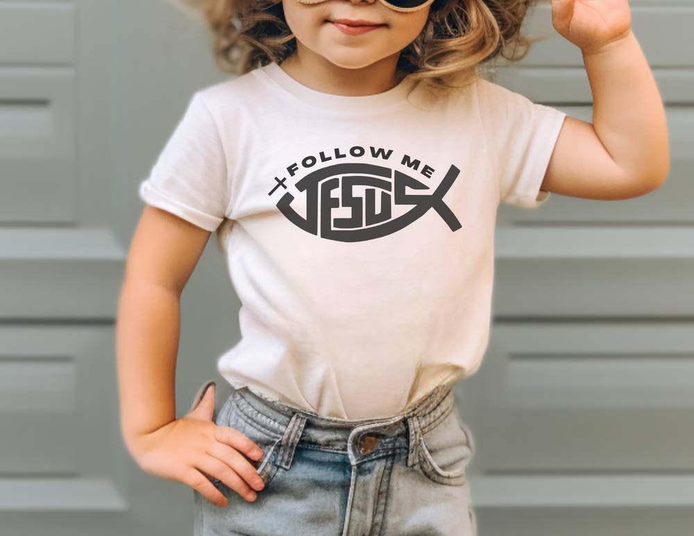 A toddler tee featuring a girl in sunglasses and a white shirt. Classic fit, high stitch density, 100% Ringspun cotton, durable double-needle collar, sleeve, and bottom hems. Title: Jesus Follow Me Toddler Tee.
