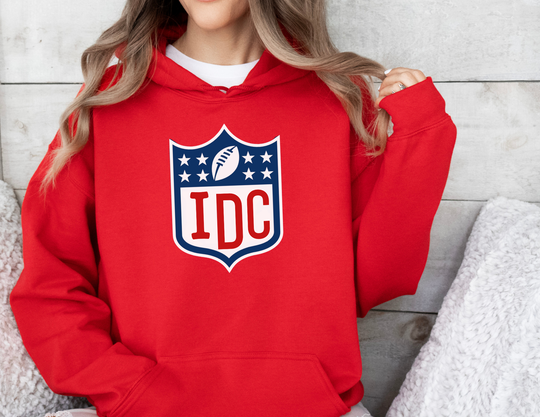 A cozy NFL I Don't Care Hoodie, featuring a football team logo on a woman in a red sweatshirt. Unisex, cotton-polyester blend, kangaroo pocket, classic fit. Perfect for comfort and style.