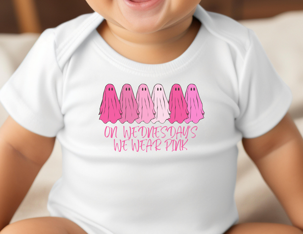 A baby wearing a white long-sleeved onesie with pink ghosts, featuring plastic snaps for easy changing. Made of 100% combed ring-spun cotton for softness and durability. From 'Worlds Worst Tees'.