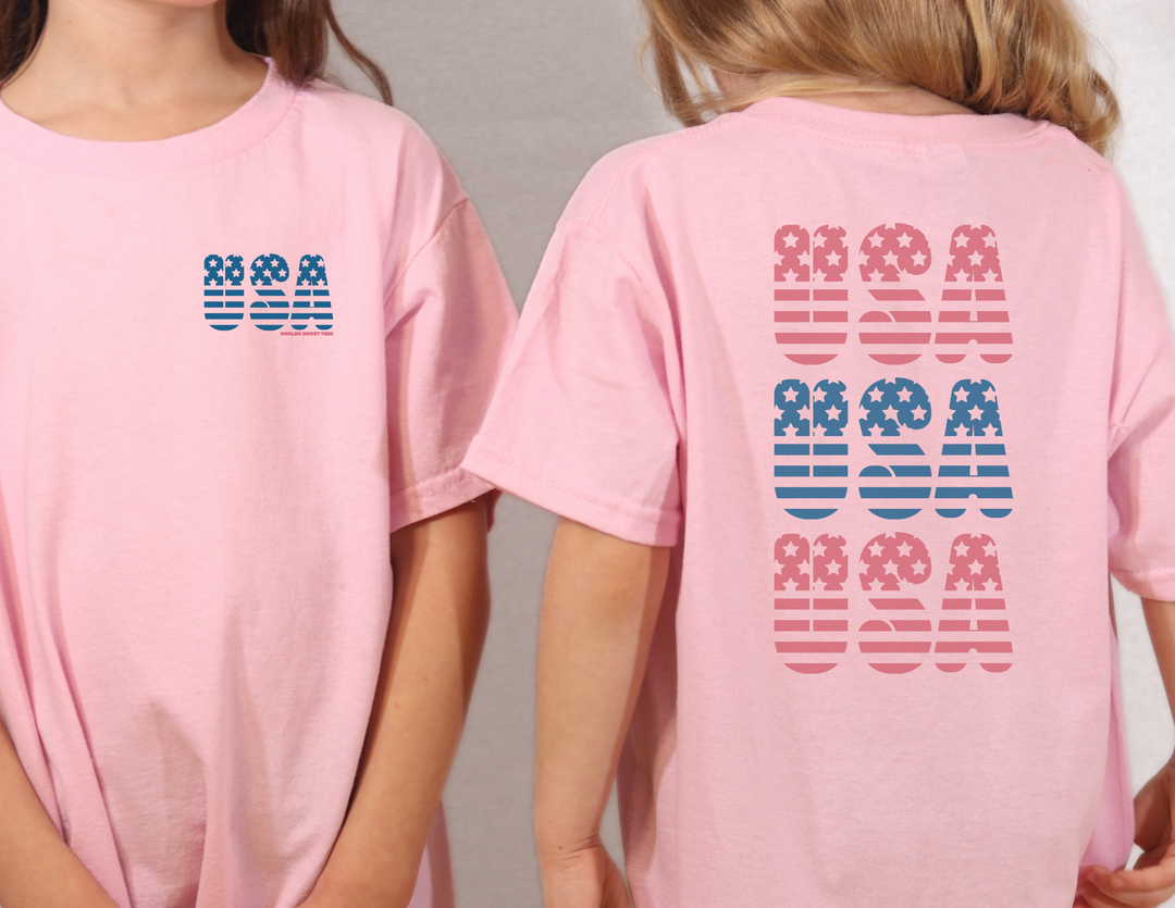 Two girls in pink shirts showcase the USA USA USA Tee from Worlds Worst Tees. Unisex heavy cotton tee with no side seams, tape on shoulders, and ribbed knit collar for a classic fit.