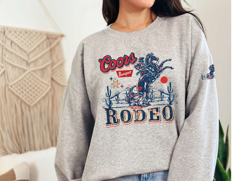 A cozy unisex heavy blend crewneck sweatshirt, the Coors Rodeo Crew, offers comfort and style. Made of 50% Cotton 50% Polyester with ribbed knit collar, loose fit, and no itchy side seams. Ideal for any occasion.