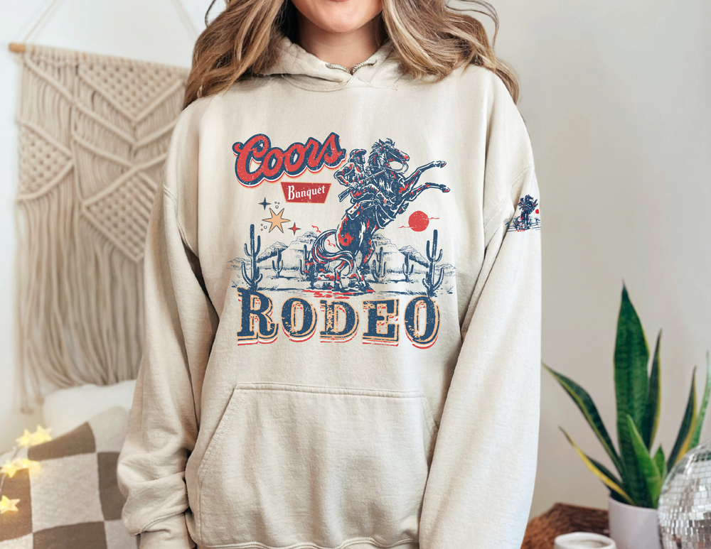 A cozy Coors Rodeo Hoodie, unisex heavy blend, cotton-polyester fabric, kangaroo pocket, no side seams, classic fit, medium-heavy fabric, tear-away label, true to size.