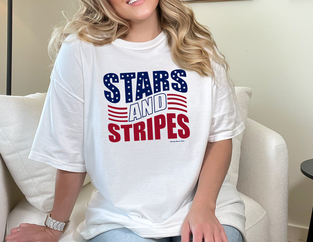 A woman in a classic Stars and Stripes Tee, sitting on a chair, showcasing the shirt's fit and quality. Unisex jersey tee with ribbed knit collars, taping on shoulders, and 100% Airlume combed cotton.