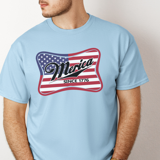 A man in a blue Merica Tee, showcasing a casual shirt with no side seams for comfort. Unisex, heavy cotton fabric with ribbed knit collar and tape on shoulders for durability. Classic fit, versatile wardrobe essential.