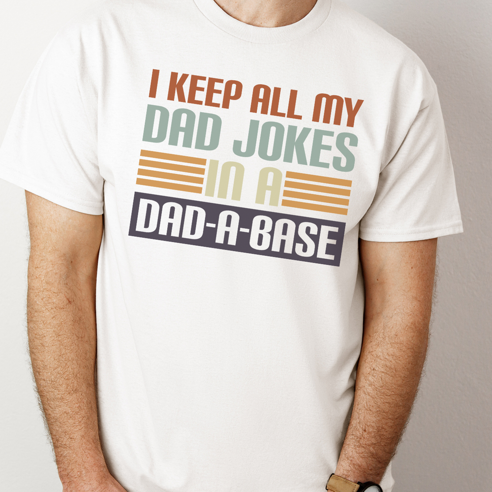 A premium Dad Jokes Tee for men, featuring a classic white shirt with a logo close-up. Combed, ring-spun cotton, ribbed knit collar, and roomy fit for comfort and style. Sizes XS to 4XL.