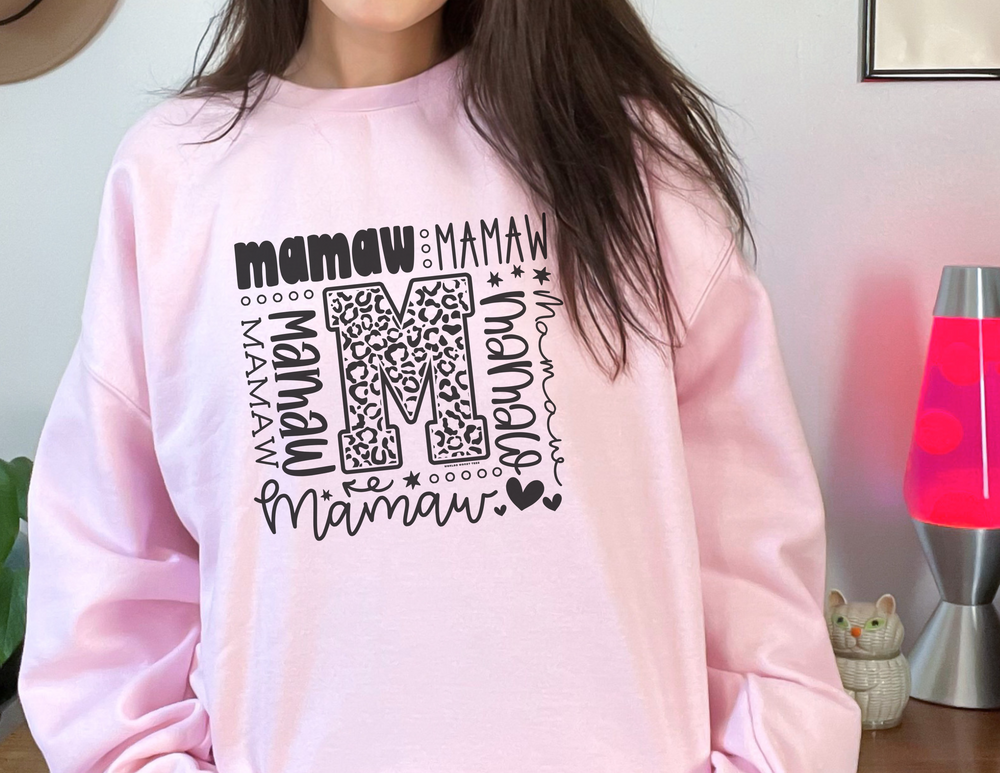 A cozy Mamaw Crew unisex sweatshirt in pink, featuring a ribbed knit collar and durable double-needle stitching. Made from a blend of 50% cotton and 50% polyester for comfort and style.