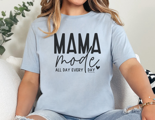 A woman in a relaxed fit Mama Mode Tee, crafted from 100% ring-spun cotton. Garment-dyed for coziness, featuring double-needle stitching for durability and a seamless design for a tubular shape.