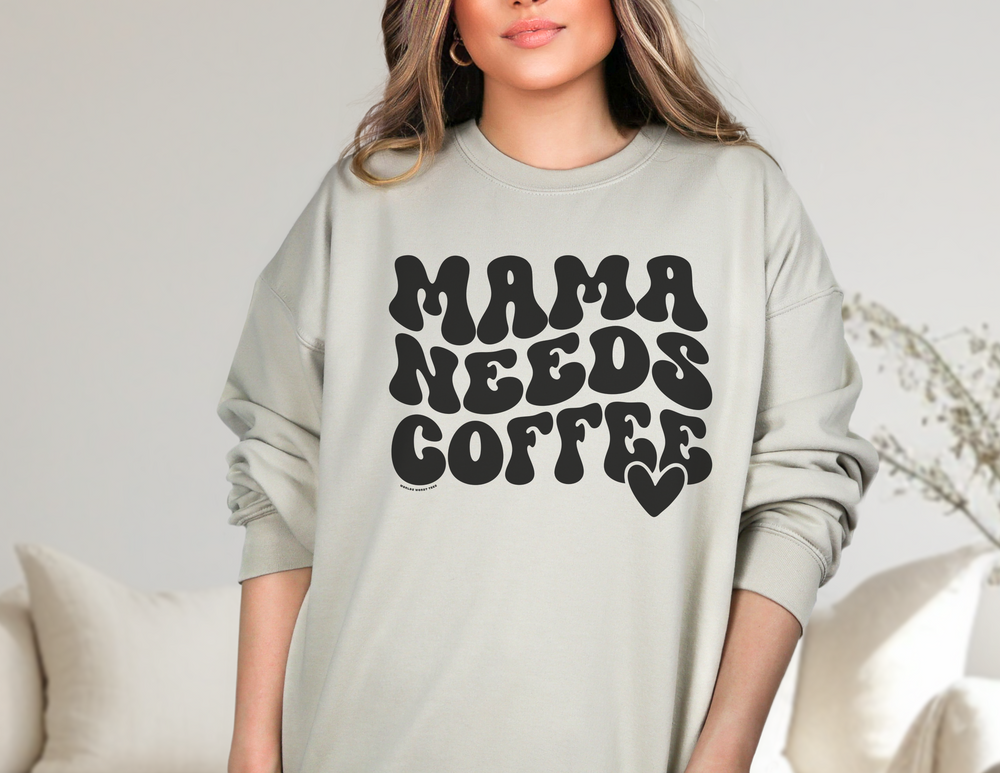 A cozy Mama Needs Coffee Crew unisex sweatshirt, featuring ribbed knit collar, no itchy side seams, 50% cotton, 50% polyester blend, loose fit, and medium-heavy fabric. Sizes range from S to 5XL.