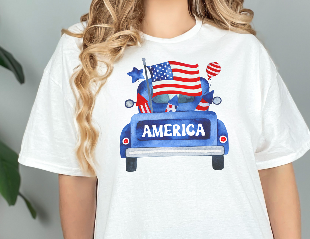 A unisex jersey tee featuring an American truck design with flags and balloons. Made of 100% cotton, it offers a retail fit, ribbed knit collars, and taping on shoulders for durability. From Worlds Worst Tees.