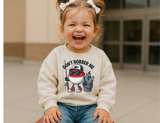 Toddler in Don't Bobber Me sweatshirt, featuring a fun cartoon bobber character with accessories, showcasing Worlds Worst Tees' playful, unique style.