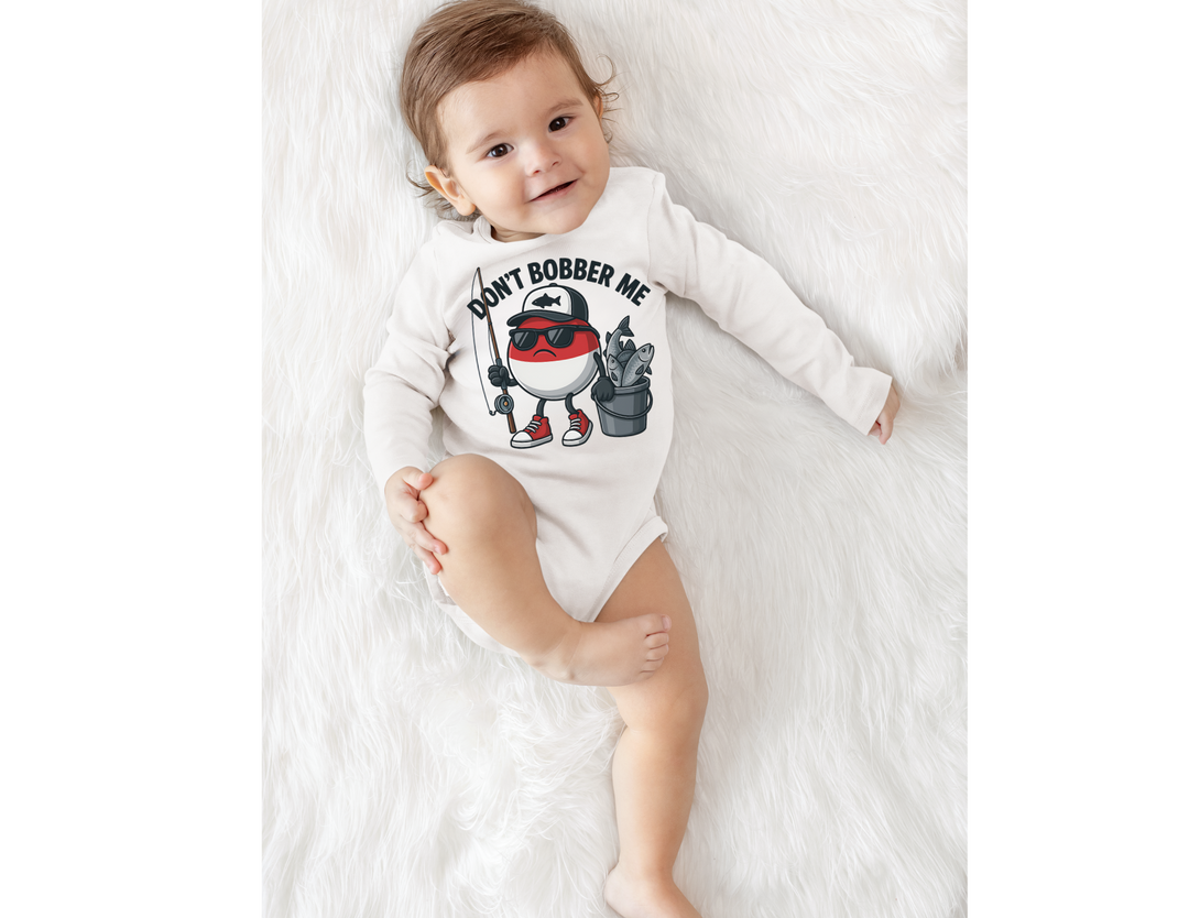 Baby in Don't Bobber Me long sleeve onesie with cartoon fishing bobber, sunglasses, holding fishing rod, highlighting playful design and easy-change snaps.
