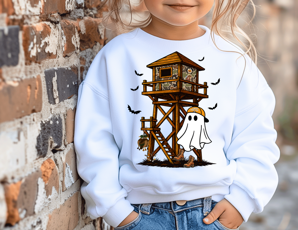 Child in oversized Ghost Hunter sweatshirt with playful Halloween-meets-hunting design, featuring a cartoon ghost and camo hunting blind, leaning against a brick wall.