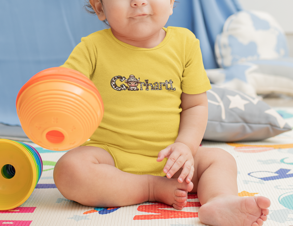 A baby wearing a Cowhartt Cow Onesie, sitting on a colorful carpet surrounded by toys. This infant fine jersey bodysuit is 100% cotton, with ribbed knitting for durability and plastic snaps for easy changing.