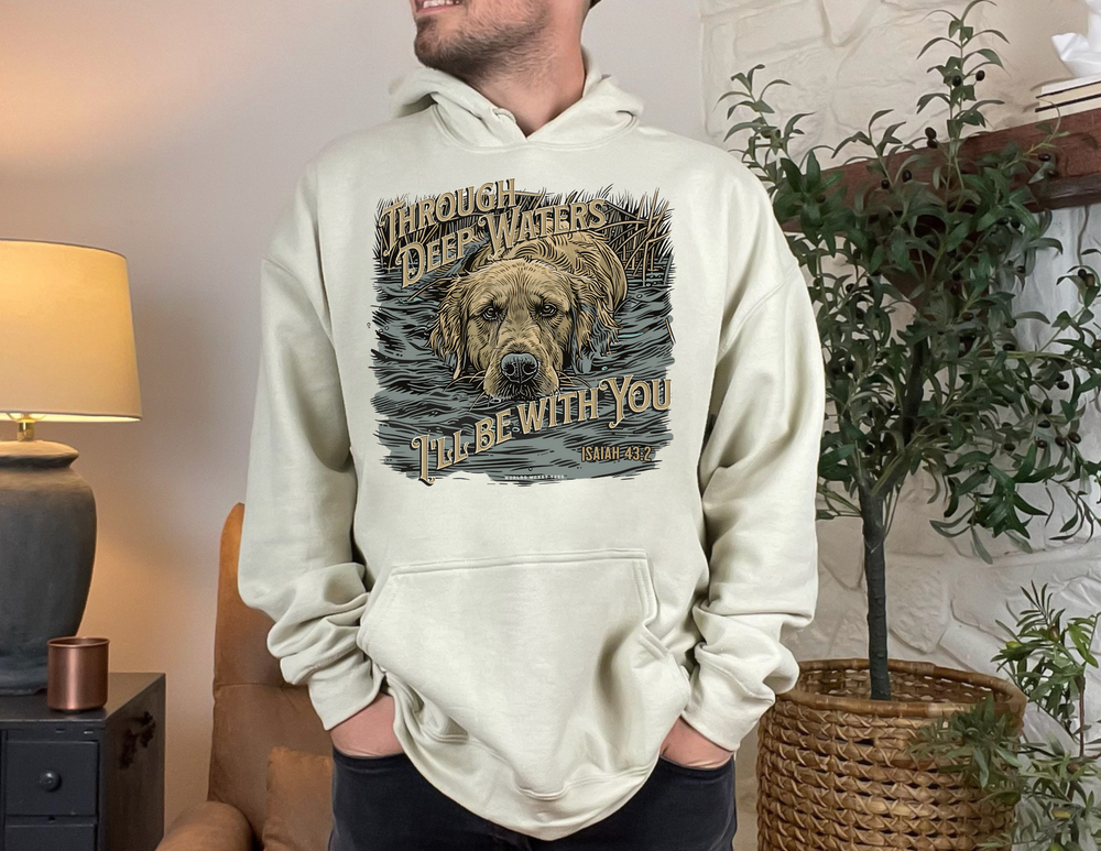 A man in a Through Deep Waters Hunting Hoodie, with a dog, indoors. Unisex heavy blend hooded sweatshirt in cotton/polyester, classic fit, kangaroo pocket, tear-away label. From 'Worlds Worst Tees'.