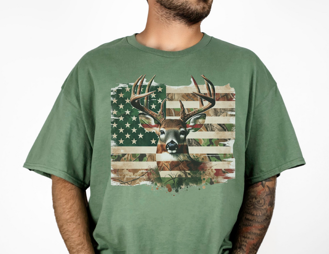 A relaxed fit Deer Flag Tee in green, featuring a deer head and flag design. Made of 100% ring-spun cotton, garment-dyed for extra coziness. Durable double-needle stitching, no side-seams for a tubular shape.