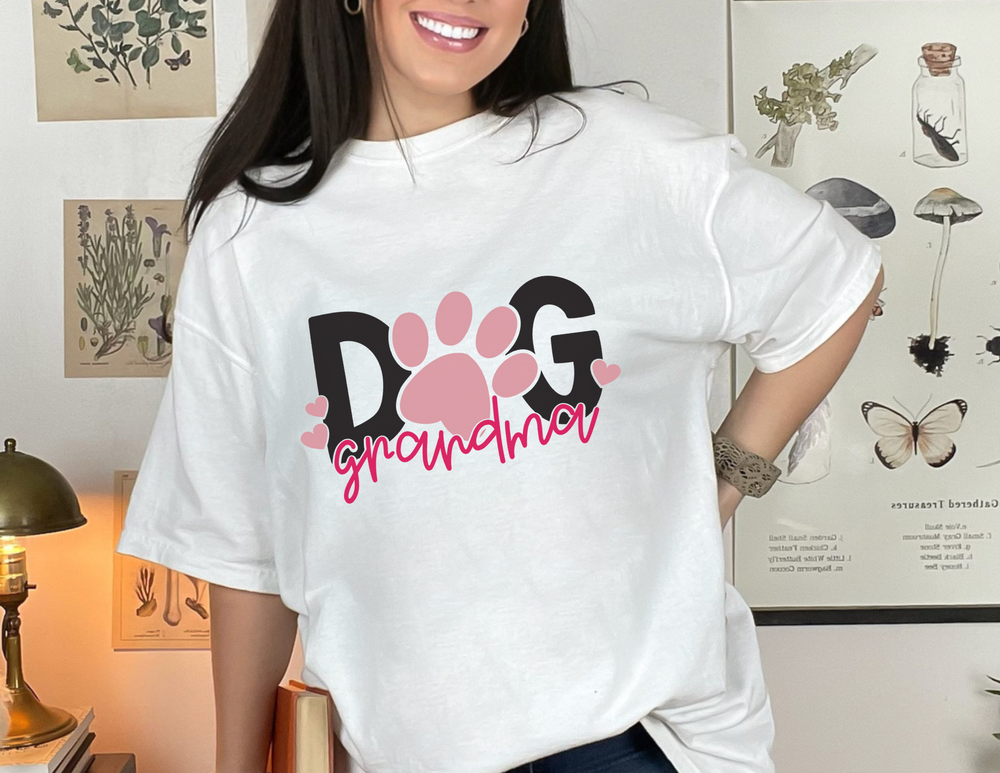 A smiling woman in a Dog Grandma Tee, a 100% ring-spun cotton garment-dyed t-shirt. Relaxed fit, soft-washed fabric, double-needle stitching for durability, and seamless design for comfort. From Worlds Worst Tees.