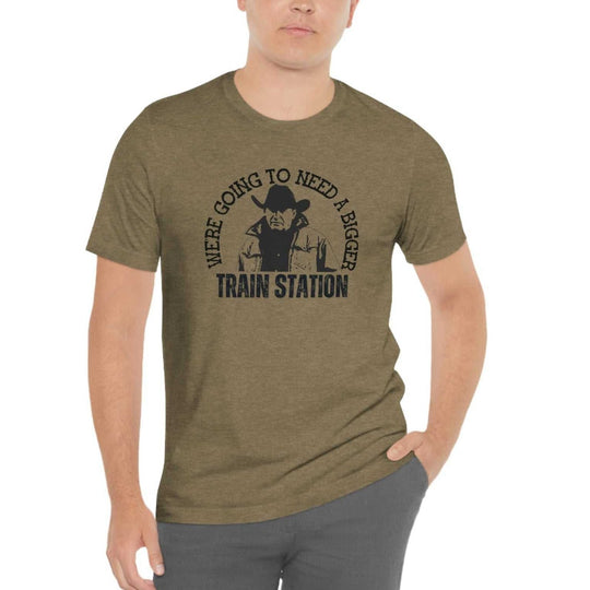 A man in a t-shirt and cowboy hat poses, showcasing the premium We're Going to Need a Bigger Train Station Tee from Worlds Worst Tees. Comfy, light, ribbed knit collar, roomy fit.