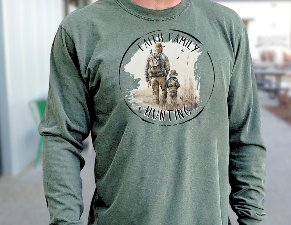 A man in a green Faith Family Hunting Long Sleeve T-Shirt, walking in a field with a child. Made of 100% ring-spun cotton for softness and style. Classic fit, garment-dyed fabric for comfort.
