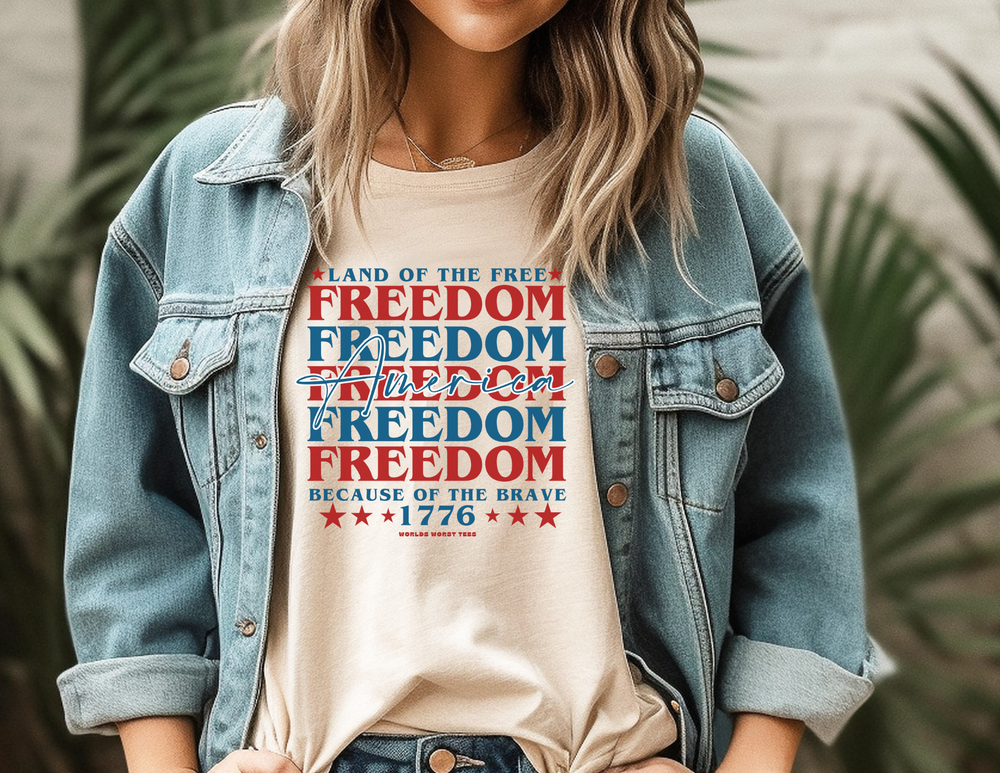 A unisex American Freedom Tee featuring a woman in a denim jacket. Classic jersey tee with ribbed knit collar, Airlume combed cotton, and quality print. Retail fit, true to size.