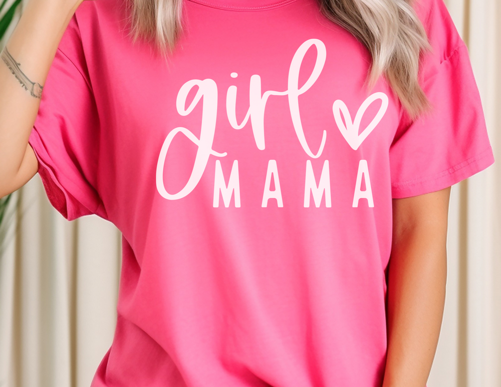 A relaxed fit Girl Mama Tee in pink, featuring a white heart and letter design. Made from 100% ring-spun cotton for comfort and durability. Ideal for daily wear with a soft-washed, cozy feel.