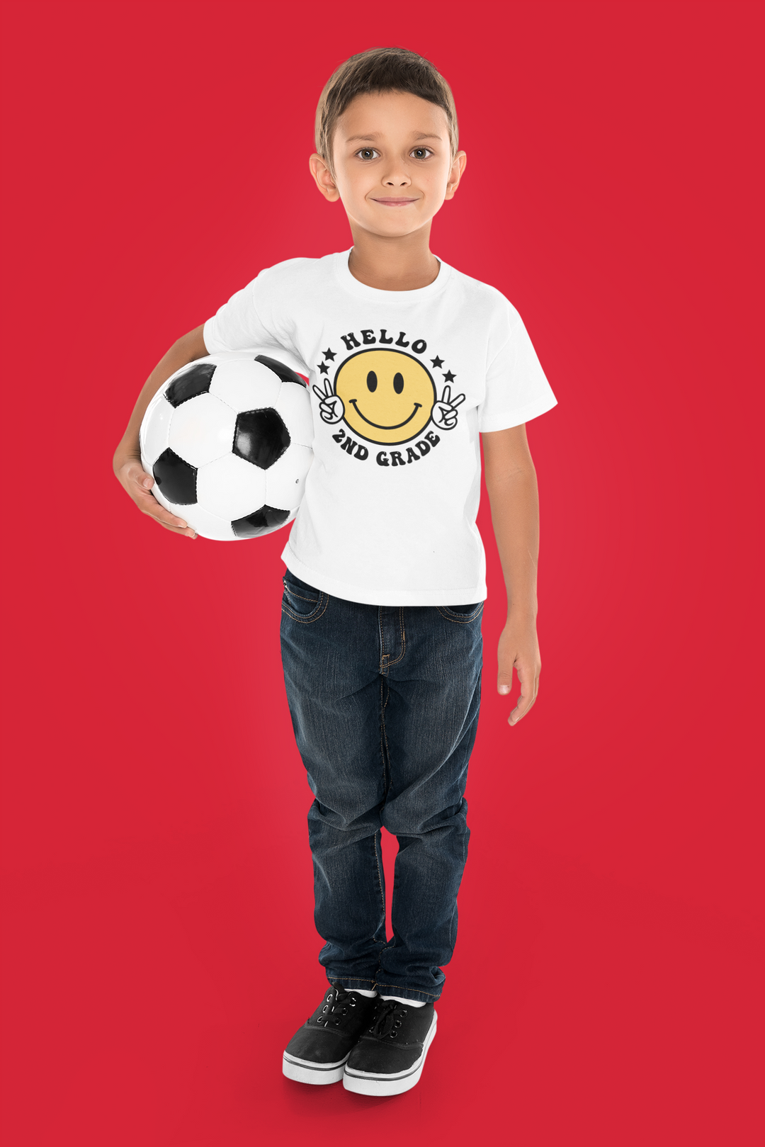 A boy holding a football ball, wearing a Hello 2nd Grade Kids Tee from Worlds Worst Tees. Made of 100% cotton, light fabric, classic fit, tear-away label, and durable twill tape shoulders.