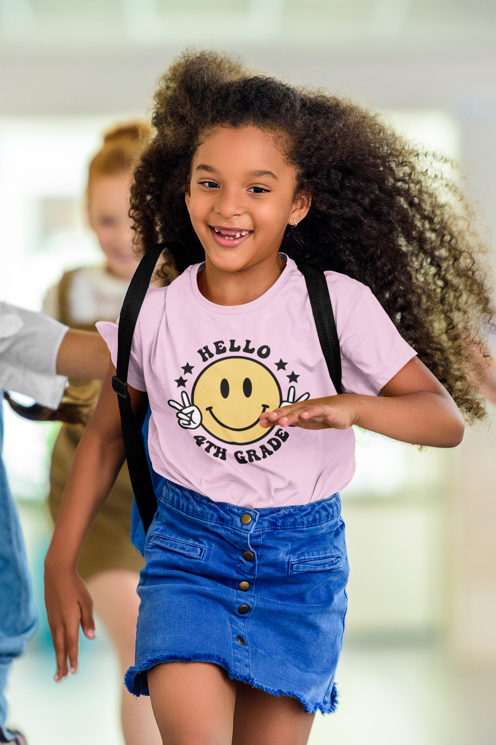 A girl with long curly hair running in a Hello 4th Grade Kids Tee, a 100% cotton tee perfect for everyday wear. Features twill tape shoulders and ribbed collar for durability. Classic fit, tear-away label.