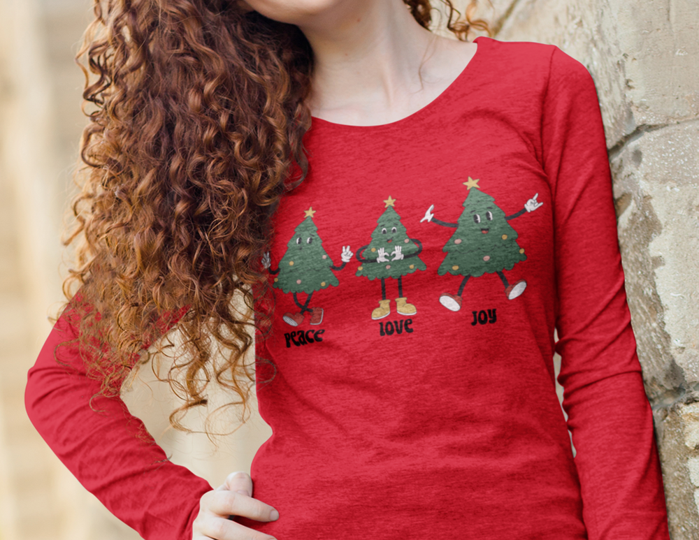 A woman in a red Peace Love Joy Long Sleeve Tee with curly hair. Classic fit, 100% cotton, no side seams, taped shoulders for durability. Medium fabric, environmentally friendly. From Worlds Worst Tees.