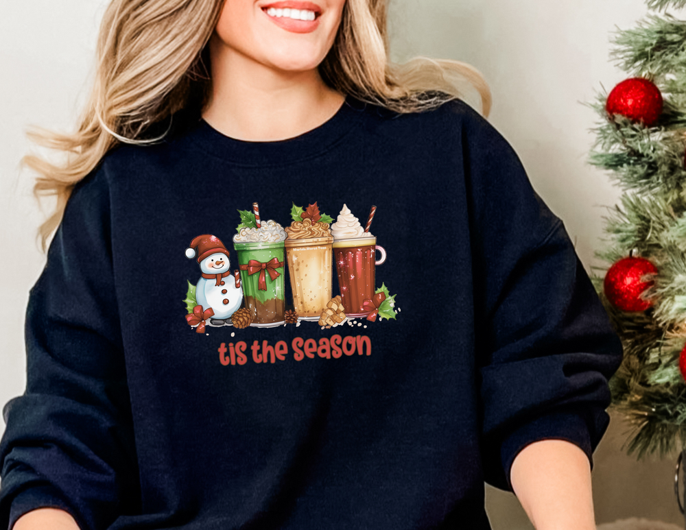 A cozy unisex Christmas crewneck sweatshirt featuring a woman in a black sweater with milkshakes and snowman design. Ideal for festive comfort, with ribbed knit collar and polyester-cotton blend. Sizes S-5XL.