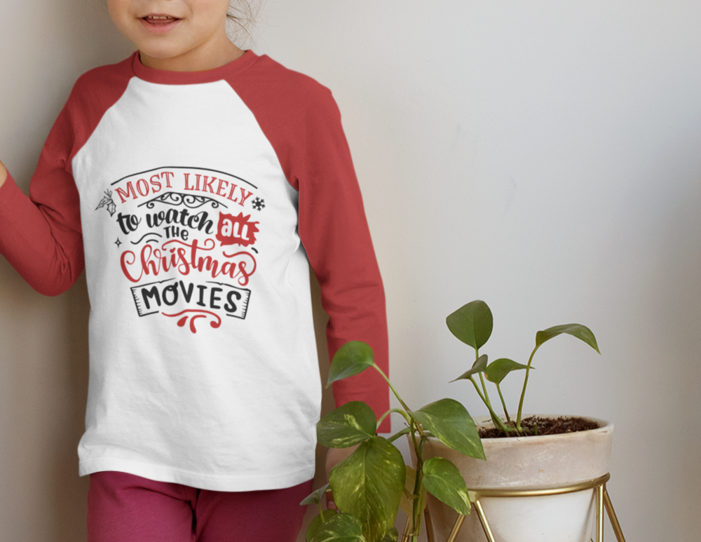 A girl stands near a houseplant, a person in a red and white shirt. A plant in a pot. A hand holds a shirt with red and black text. A close-up of a logo. A close-up of pants. The alt text for the product image is: Watch All Christmas Movies 3\4 Raglan Tee, loose-fit unisex tee with polyester-cotton-rayon blend, light fabric, and quality print.