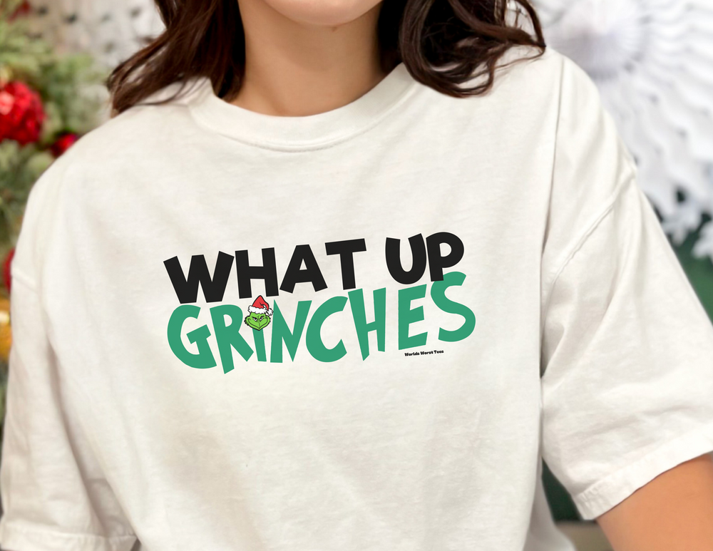 Unisex What up Grinches Tee, garment-dyed sweatshirt in white. 80% ring-spun cotton, 20% polyester, relaxed fit with rolled-forward shoulder. From Worlds Worst Tees.