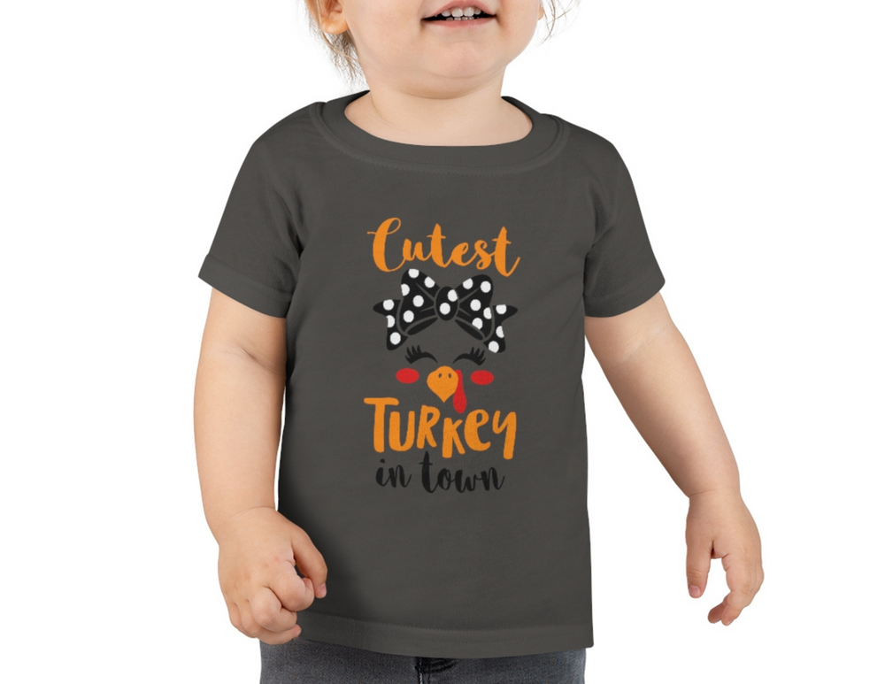A toddler in a grey Cutest Little Turkey tee, perfect for sensitive skin. Made of 100% combed ringspun cotton, light fabric, classic fit, tear-away label, true to size.