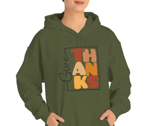 A woman in a green Give Thanks Sweatshirt, featuring a hood and kangaroo pocket. Unisex heavy blend fabric of cotton and polyester for warmth and comfort. Perfect for chilly days.