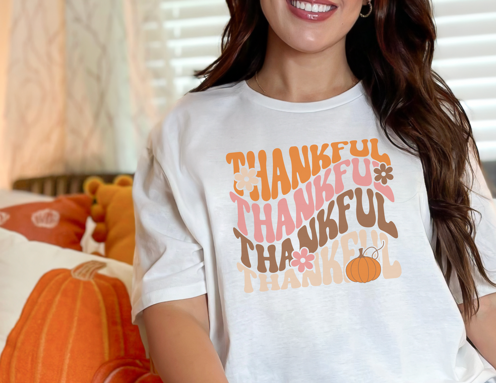 A woman smiles in a Thankful Tee, a garment-dyed t-shirt made of 100% ring-spun cotton. Relaxed fit, durable double-needle stitching, and cozy fabric for daily wear.
