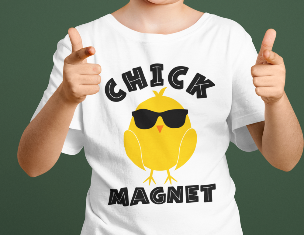A person pointing at a Chick Magnet Kids Tee, featuring a yellow chick with sunglasses. 100% cotton tee ideal for everyday wear, with twill tape shoulders and ribbed collar for durability. Classic fit, sizes XS to XL.
