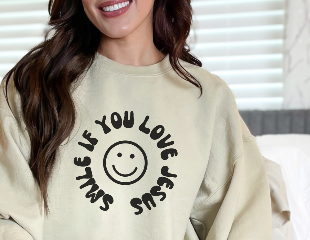 A unisex Love Jesus Crewneck sweatshirt in various sizes, featuring a smiling woman, smiley face, and person's face. Made of 50% cotton, 50% polyester with ribbed knit collar for comfort.