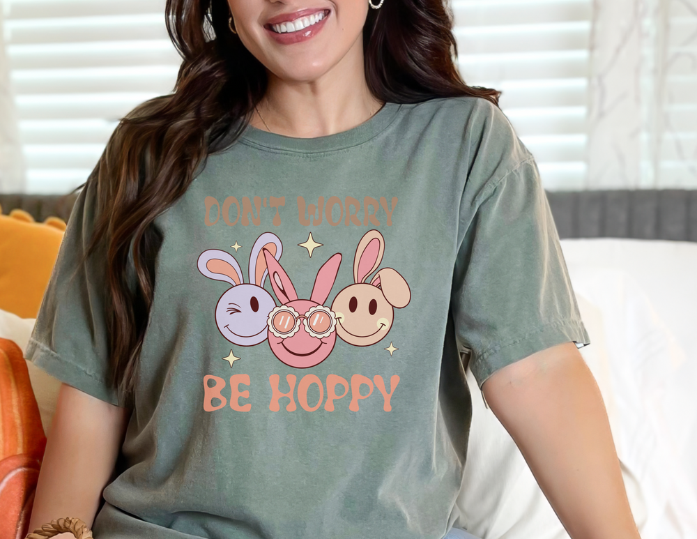 A woman in a Don't Worry be Hoppy Tee smiles, showcasing the relaxed fit garment-dyed t-shirt made of 100% ring-spun cotton. Double-needle stitching ensures durability.