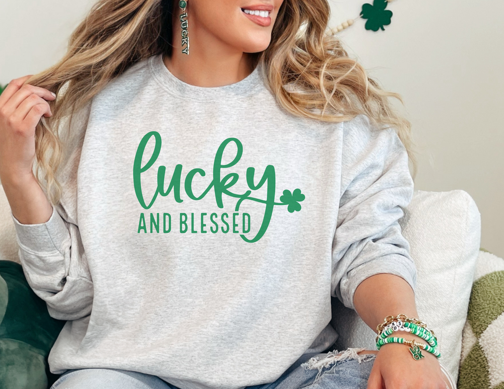 A woman in a Lucky and Blessed Crewneck, sitting comfortably on a couch. The sweatshirt is a blend of polyester and cotton, featuring a ribbed knit collar and a loose fit. Perfect for casual wear.
