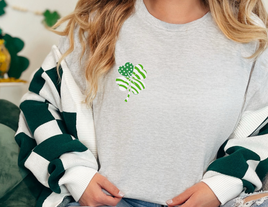 A woman wears a USA Clover Tee, a staple in any wardrobe. Unisex heavy cotton tee with no side seams, tape on shoulders for durability, and ribbed knit collar. Classic fit, 100% cotton.